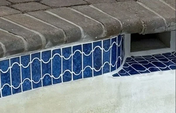 Close-up of precise waterline tile repair and replacement on an inground gunite pool.