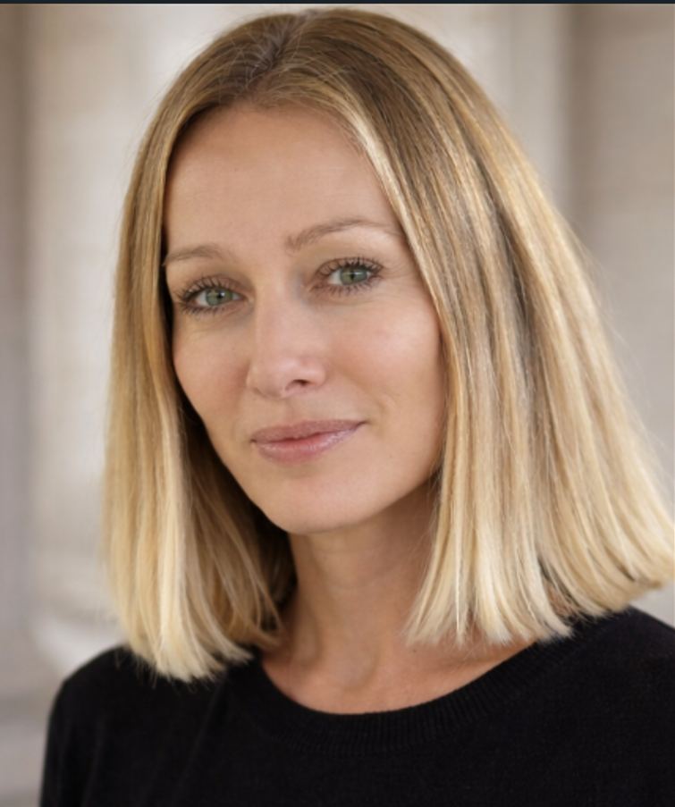 Portrait d'une femme aux cheveux blonds, yeux verts, souriant légèrement, portant un haut noir.