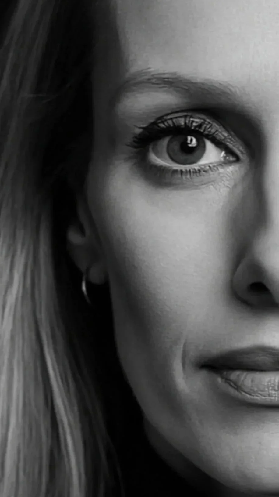 Un gros plan en noir et blanc d'un visage de femme, montrant un œil, une partie du nez, des lèvres et une partie des cheveux.