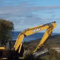 A John Deere 160 Excavator makes short work of roadside brush and small trees as it mulches them quickly, expanding right of way sightlines for drivers on each side of the road.