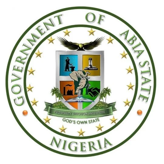 Emblem of the Government of Abia State, Nigeria, featuring a shield with symbols, an eagle at the top, golden stars surrounding, and a green banner with the motto 'Prosperity Through Enterprise' and 'God's Own State' at the bottom.