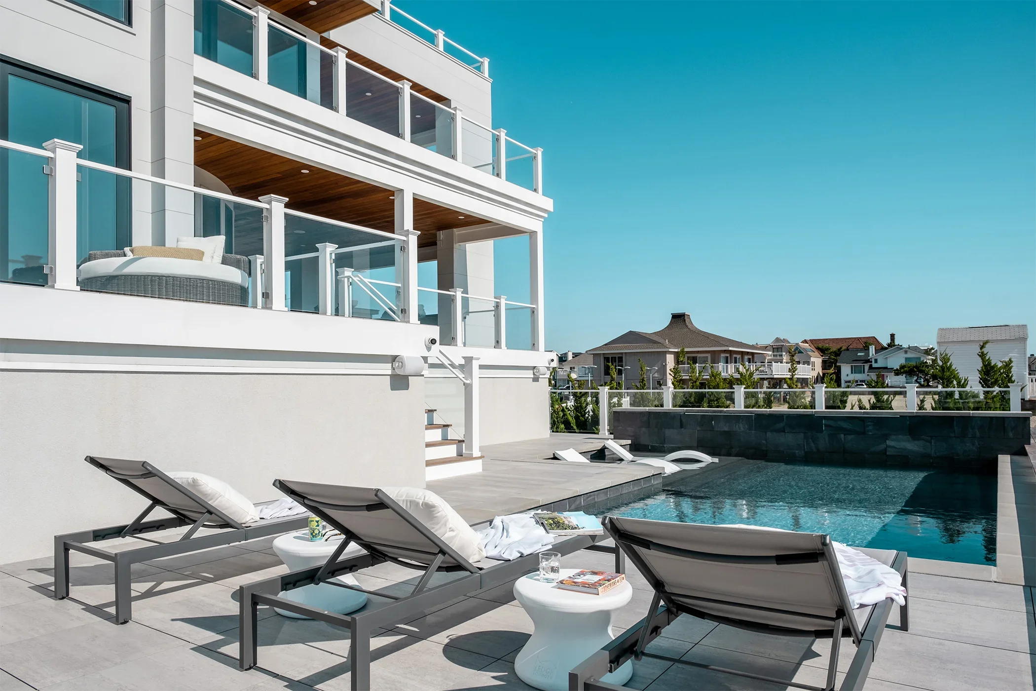 Modern rooftop terrace with pool, lounge chairs, and sunny sky.