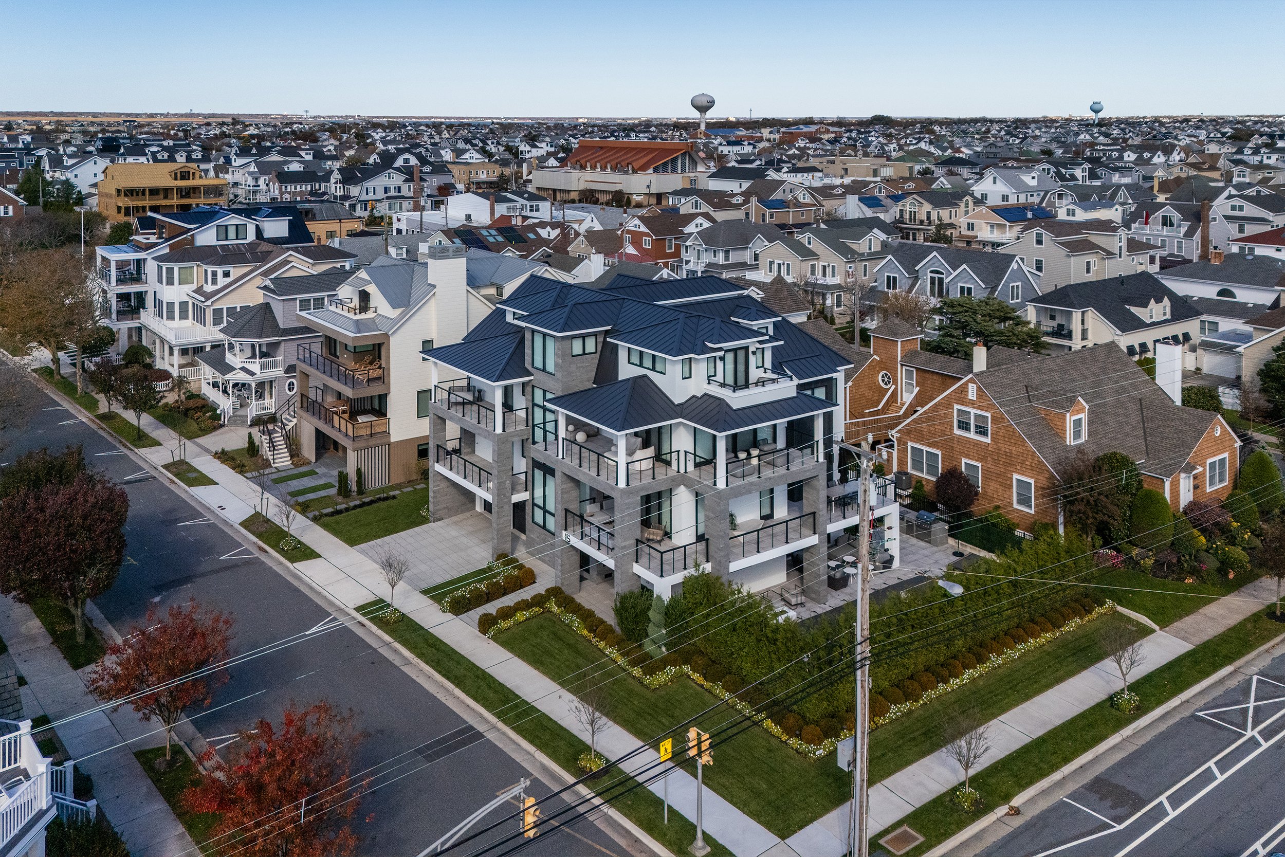 Aerial view of modern multi-story residential buildings and a neighborhood with streets, sidewalks, and trees.