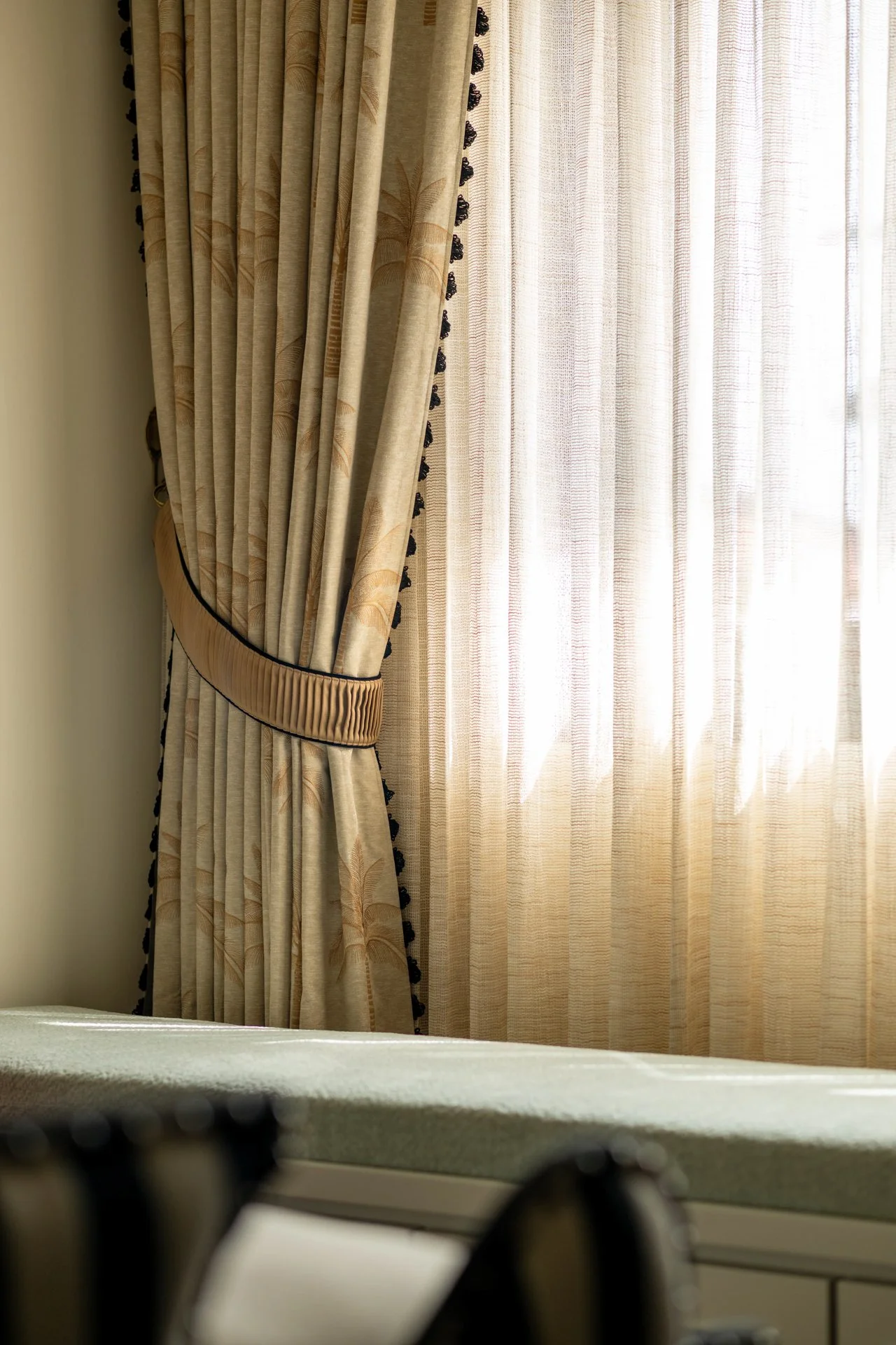 Curtains covering a window with sheer drapes behind them, sunlight filtering through.