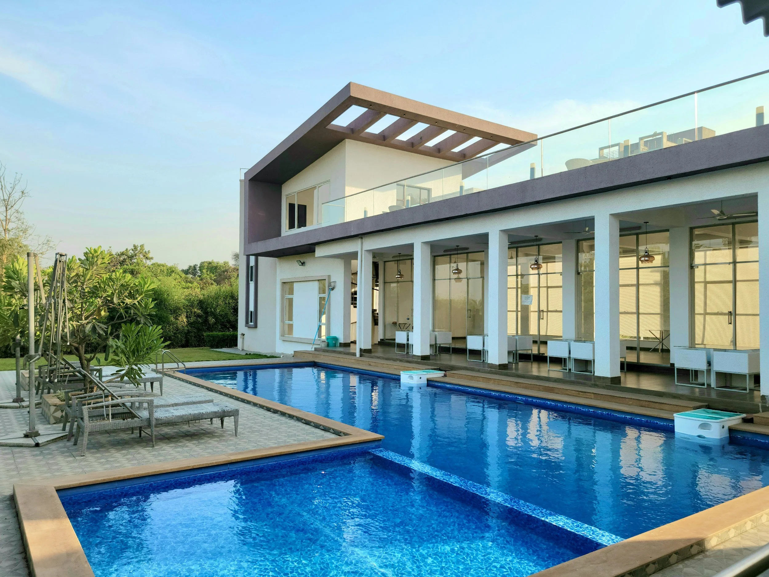 Modern house with outdoor pool, lounge chairs, and patio area.