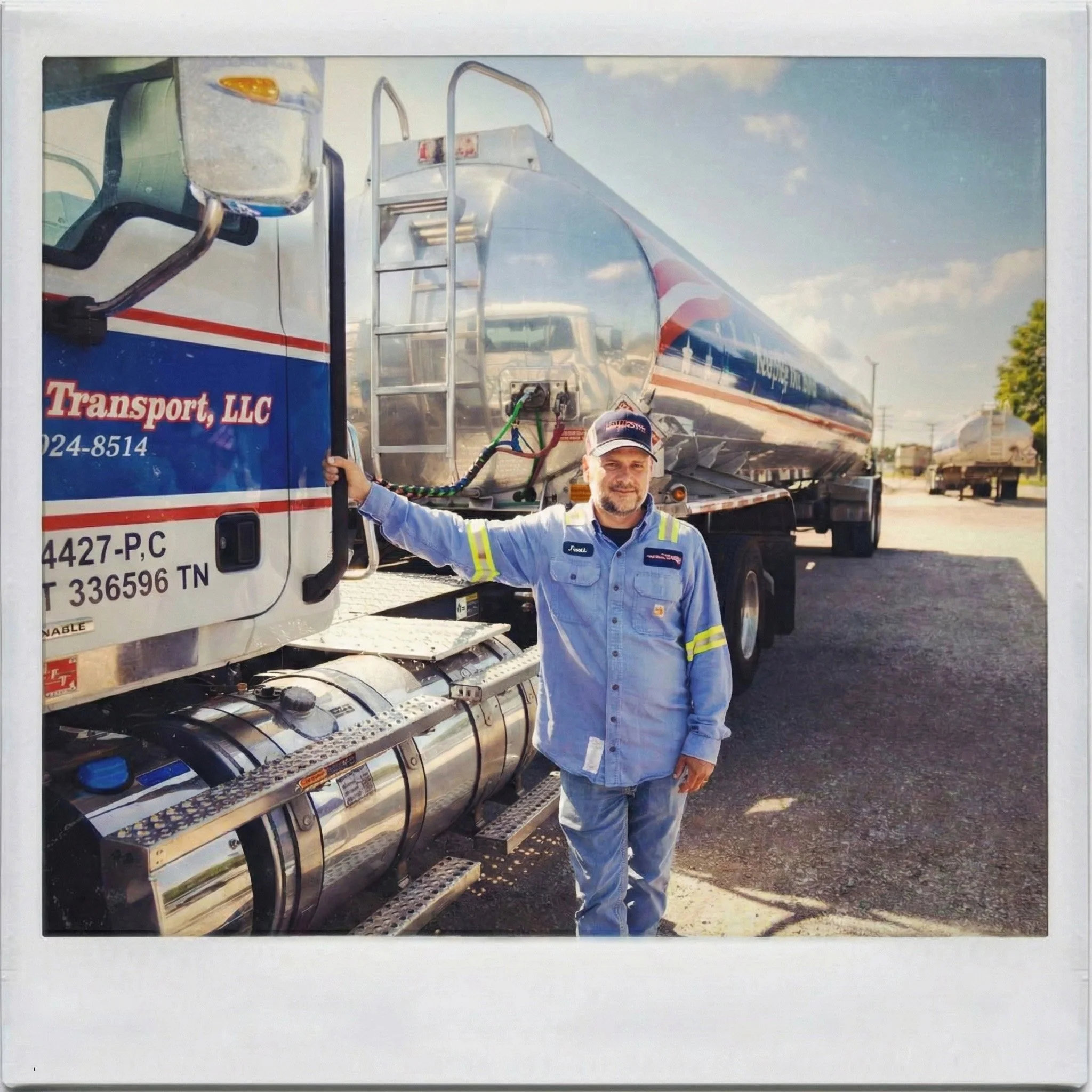 A Fuel Transport truck driver leaning against a Fuel Transport fuel truck