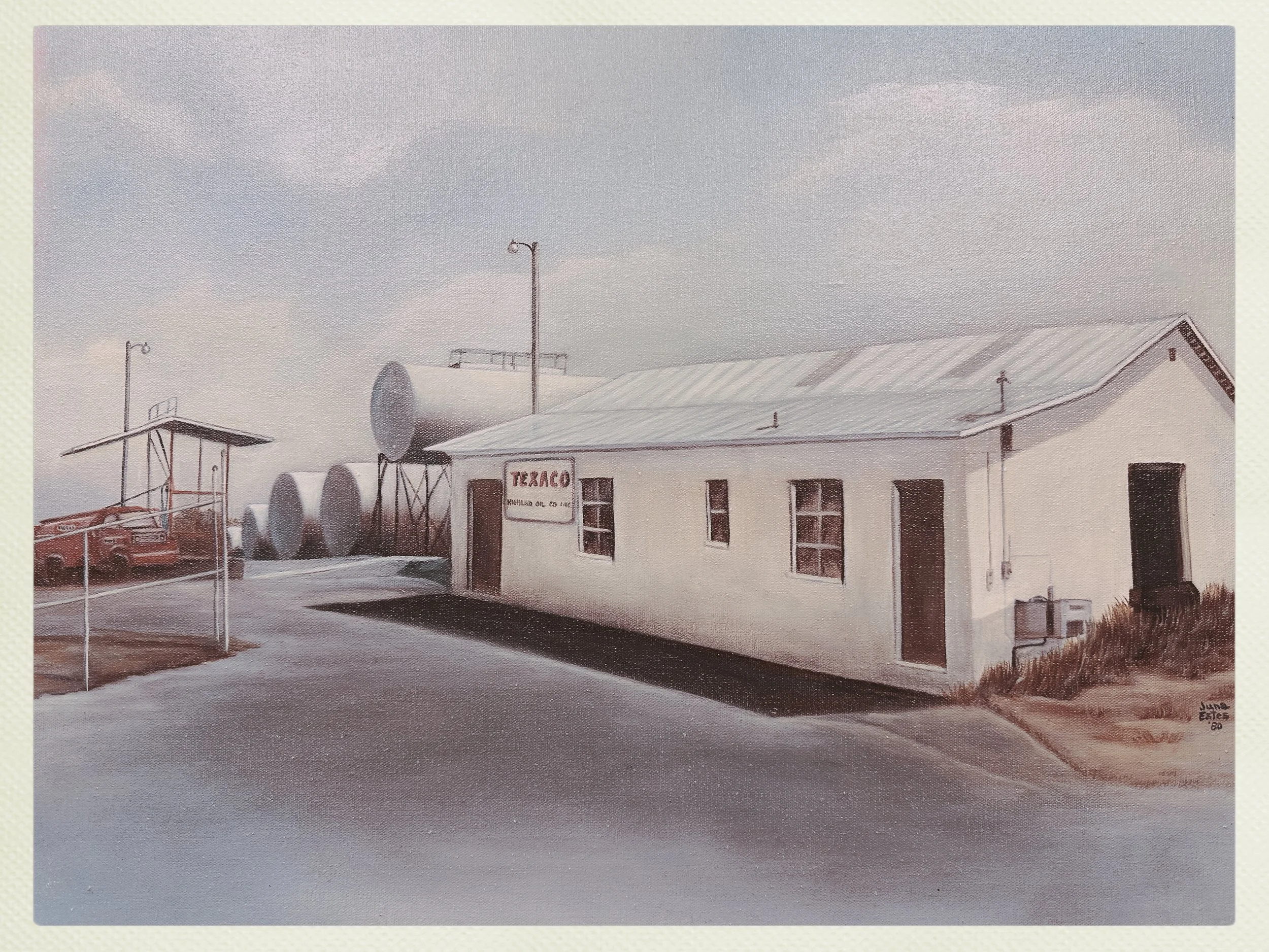 A vintage oil station with a Texaco sign, white building, and large tanks in the background, alongside a red classic car and a flagpole.