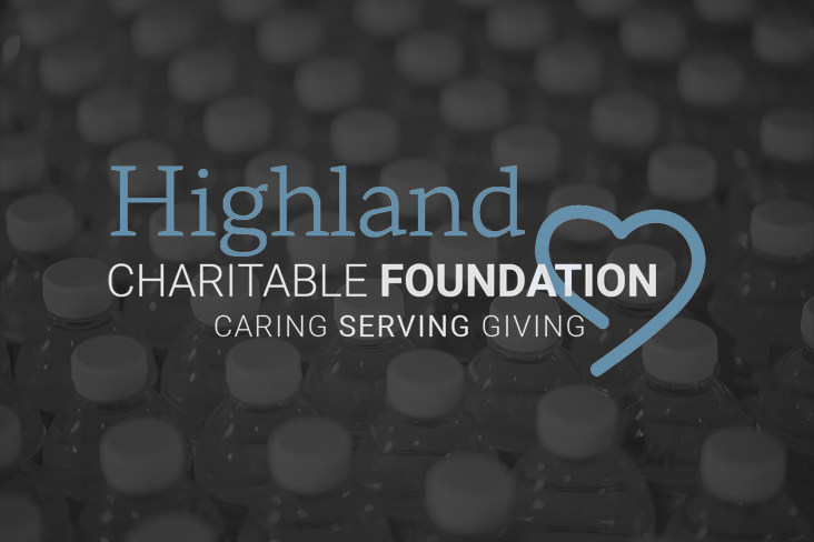 People sorting and packing donated food items for Highland Charitable Foundation, with boxes and food supplies on table.