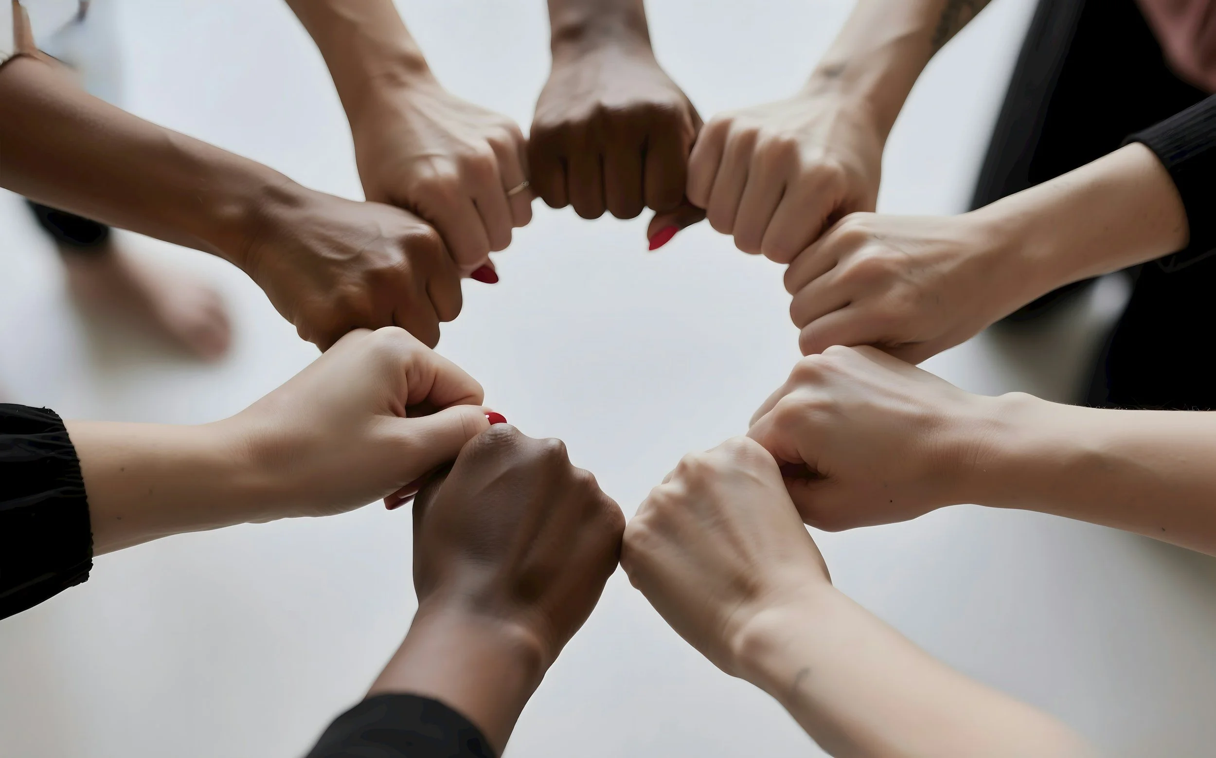 nine different hands in gentle fists, reaching in, orming a circle