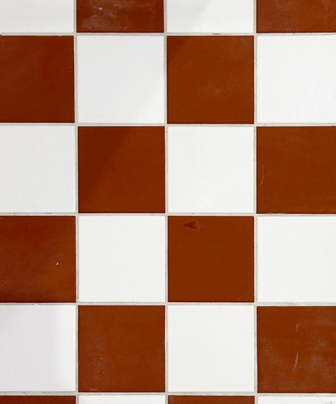 Carrelage de sol avec des carreaux blancs et marron disposés en motif alterné.