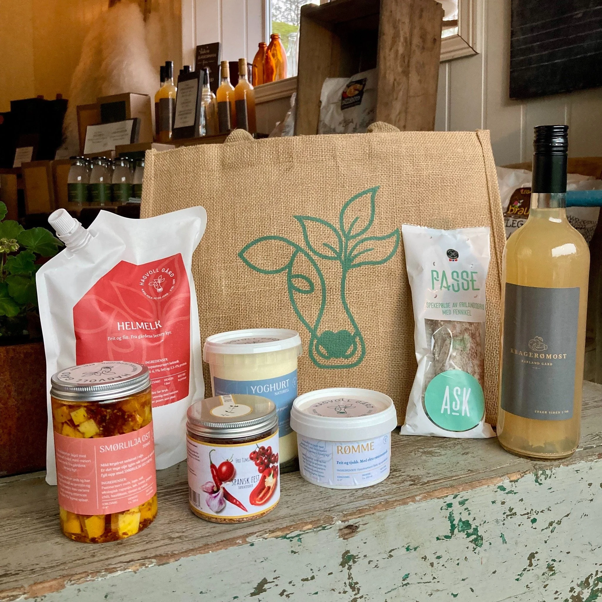 Et utvalg av matvarer og drikkevarer, inkludert små bokser, poser, og en flaske, plassert foran en veske med en dyremotiv