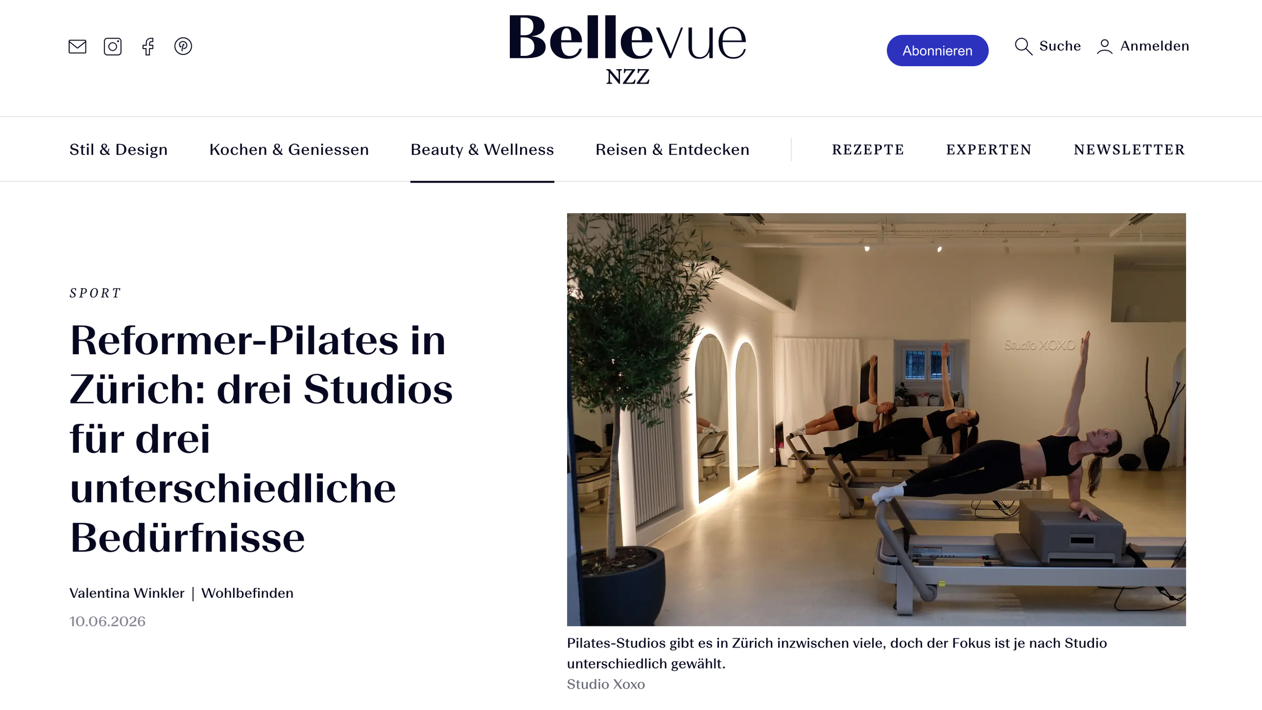 Interior of a Pilates studio with two women practicing Pilates on reformer machines, surrounded by plants and modern decor.