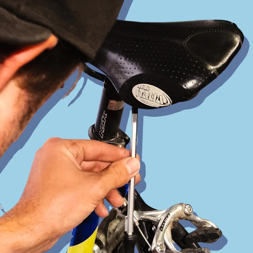 Close up of a bike mechanic using a tool to adjust a saddle on a bike.