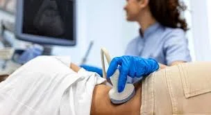 Medical professional performing an ultrasound on a patient's abdomen in a clinical setting.