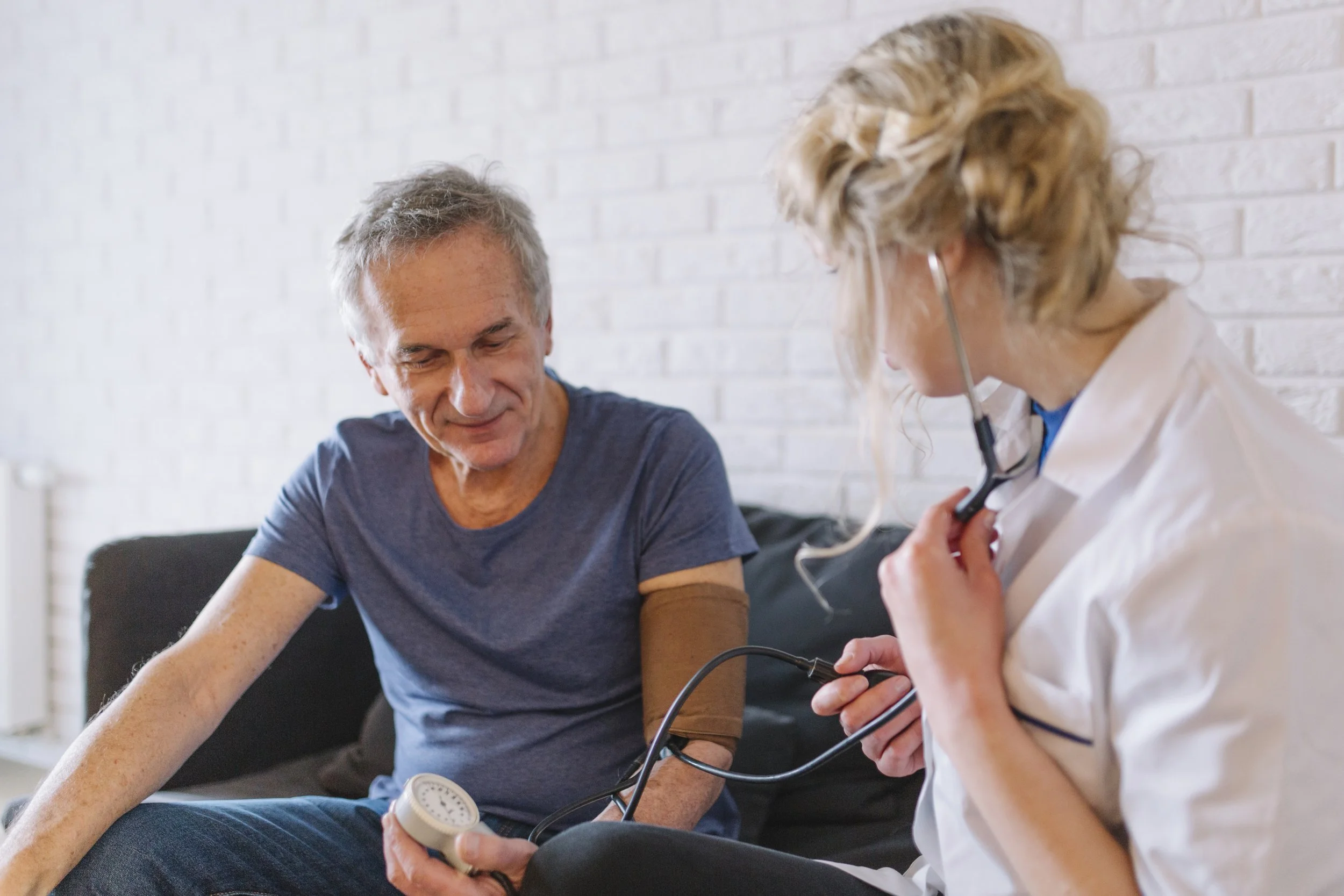 A healthcare worker checking a patient's blood pressure in a clinical setting.