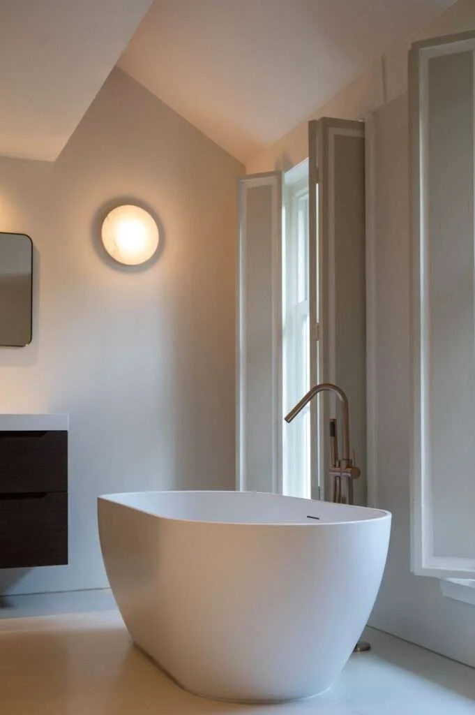 Baignoire blanche freestanding dans une salle de bain moderne avec grande fenêtre et miroir