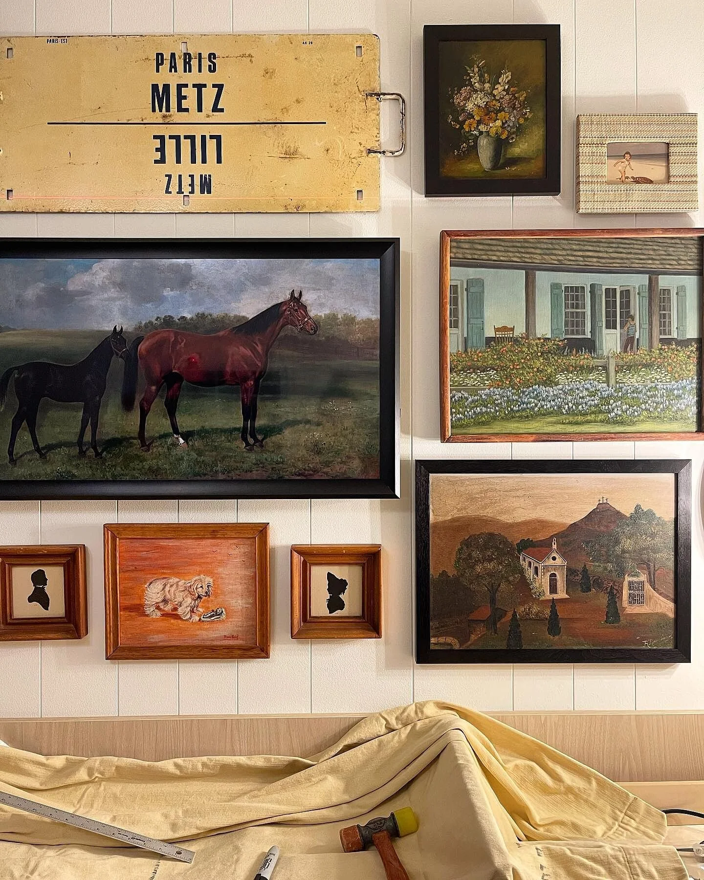 A wall of framed art, one of which is a Samsung Frame TV with a DecoArt custom frame