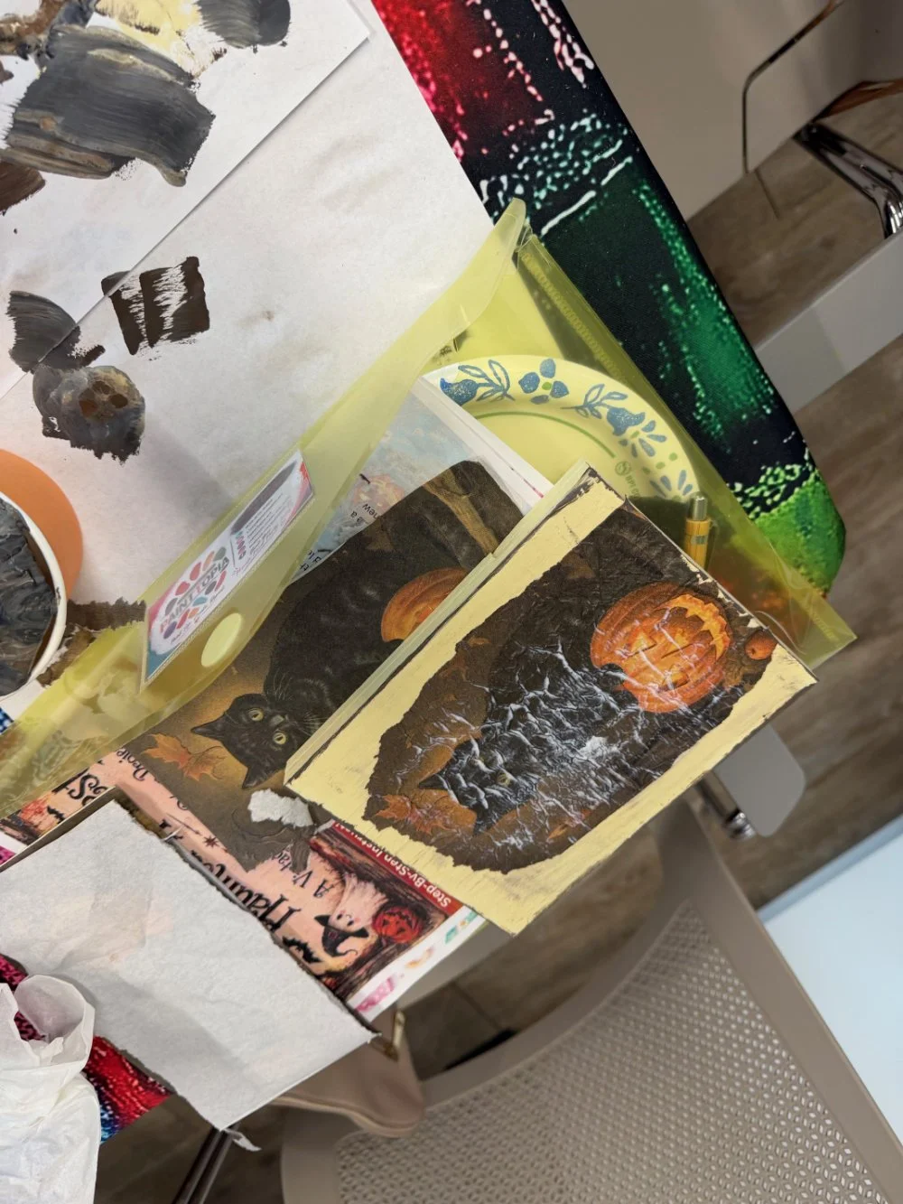 A tabletop with Halloween-themed decorations, including a picture of a carved pumpkin, black cats, and a moon, along with Halloween advertisements and paper items.