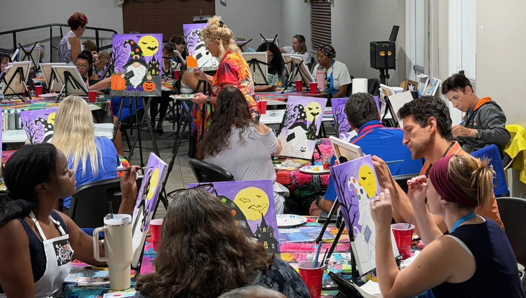 People painting Halloween-themed pictures at a group art class.