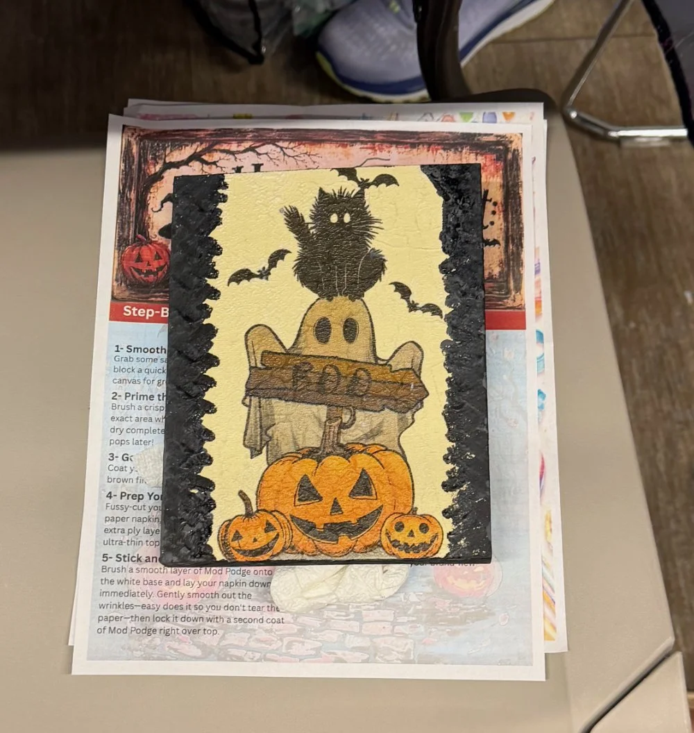 Halloween-themed greeting card featuring three carved pumpkins, a cute ghost figure, a black cat with glowing eyes sitting on a pumpkin, and a full moon in the background.