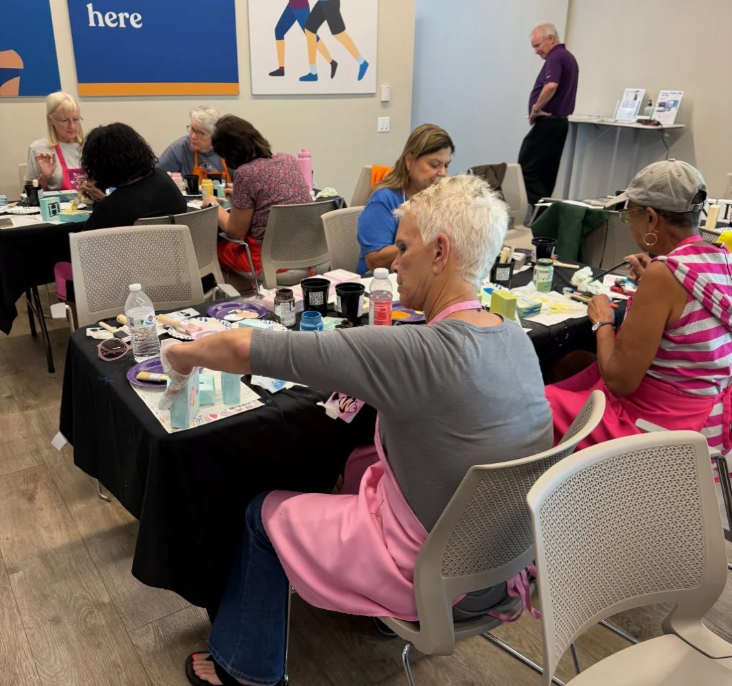 People participating in a craft workshop in a conference room, working on arts and crafts projects at tables.