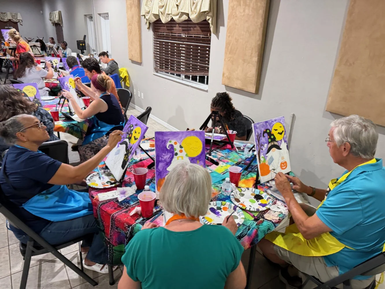 People participating in a Halloween-themed painting party, decorating canvases with spooky and festive designs.