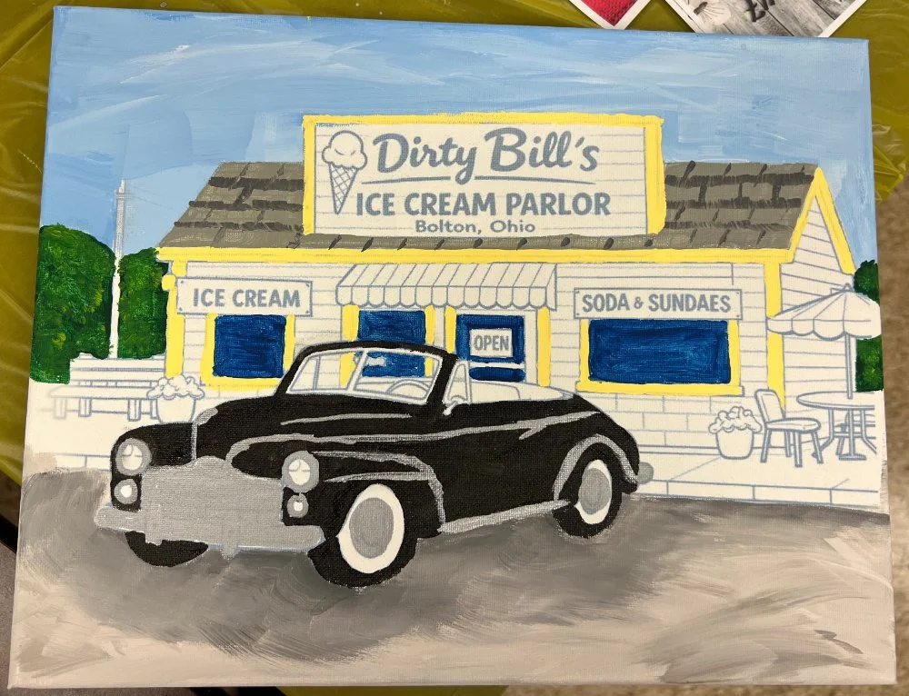 Hand-painted sign for Dirty Bill's Ice Cream Parlor in Bolton, Ohio. The illustration depicts a vintage black car parked in front of the ice cream shop, with trees and outdoor seating visible.