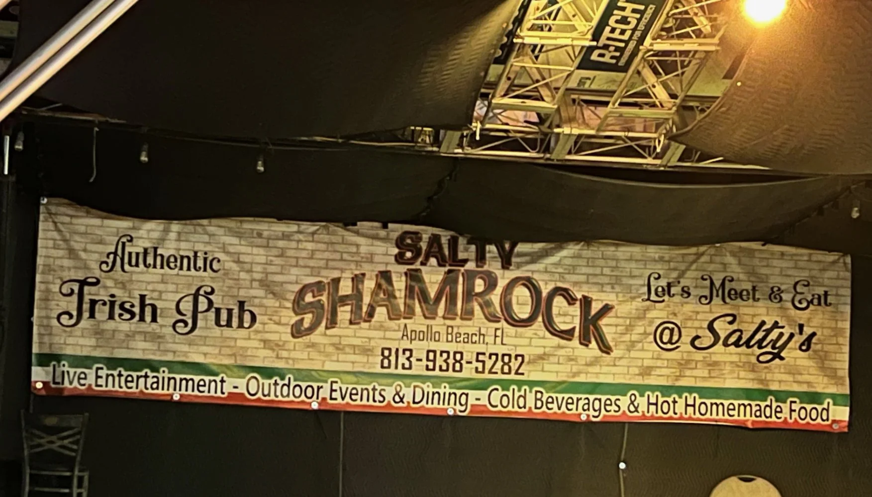 A banner for Salty Shamrock, an authentic Irish pub in Apollo Beach, FL. The banner mentions live entertainment, outdoor events, dining, cold beverages, and homemade food. It includes the phone number 813-938-5282 and invites people to meet and eat a