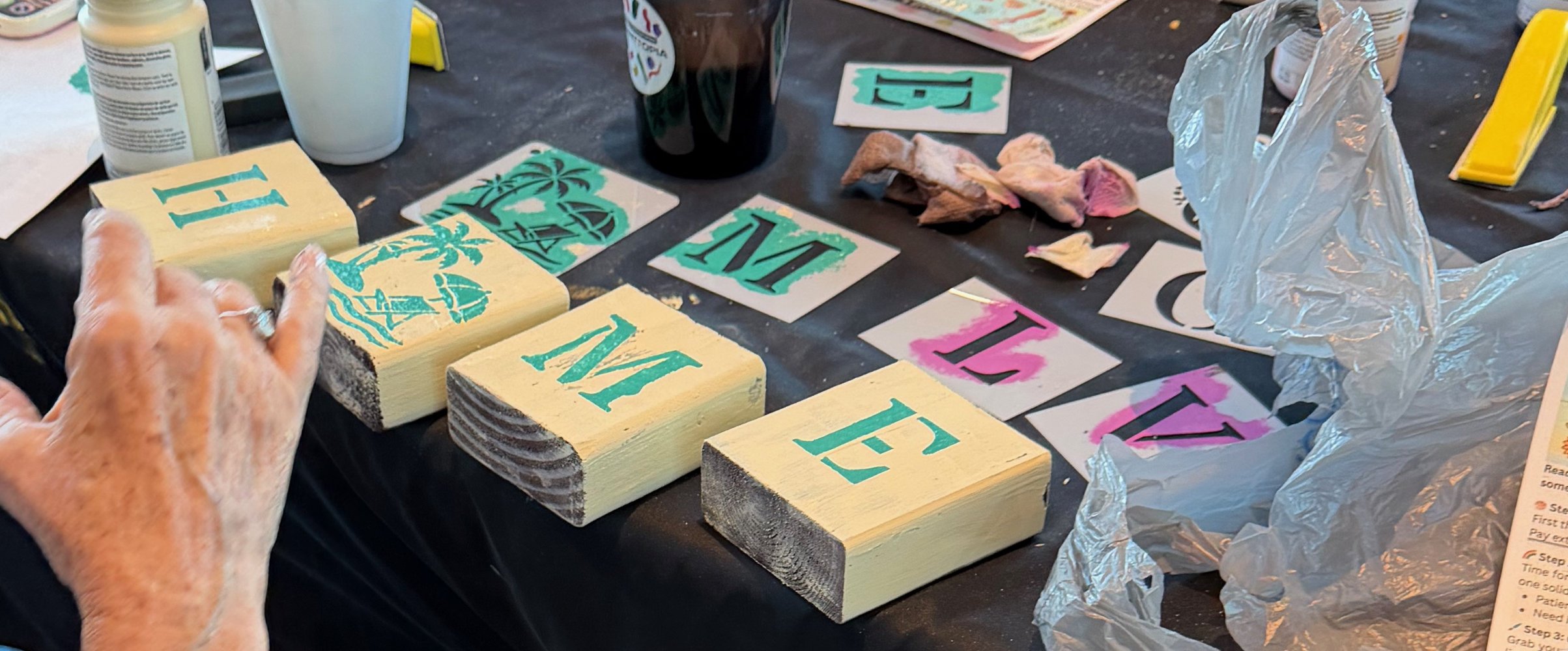 Wooden blocks painted with the word 'LOVE' and various painted and unpainted surface art pieces on a craft table.
