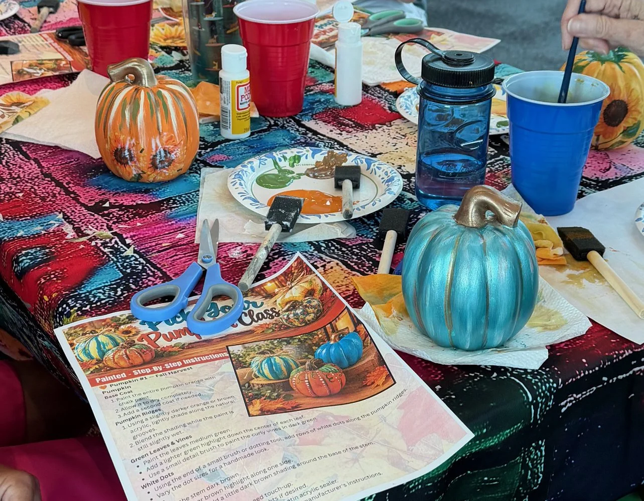 Decorated pumpkins on a table with painting supplies and instructions for a pumpkin painting activity.