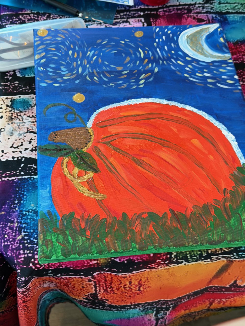 Painted canvas depicting a pumpkin with a mouse on top, set against a background of a night sky with stars and the moon.