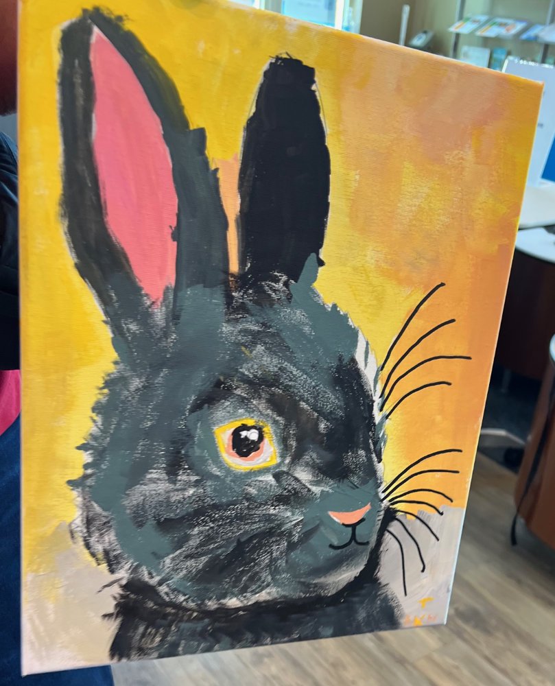 Painting of a black rabbit with pink and black ear, yellow eye, pink nose, against a yellow and orange background.