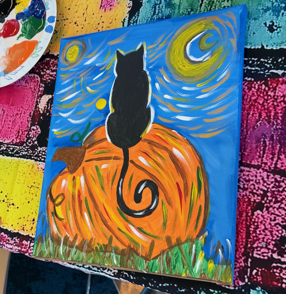 Painting of a black cat sitting on an orange pumpkin with a swirling tail, set against a starry night sky with a moon, a crescent moon, and a yellow star.