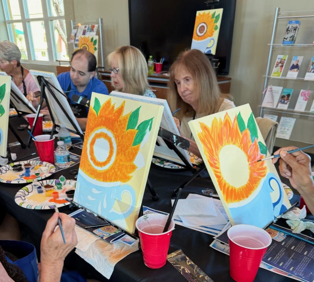 People painting sunflower-themed pictures during a paint and sip class.