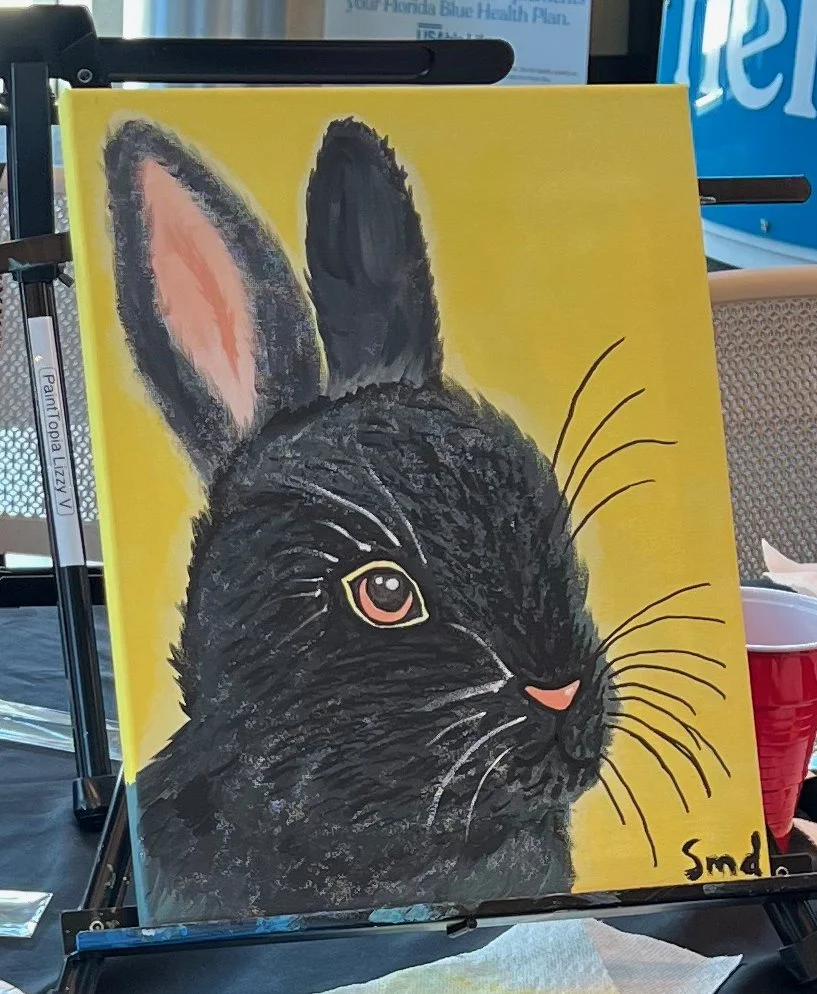 Painting of a black rabbit with pink and white eye and pink nose on yellow background.