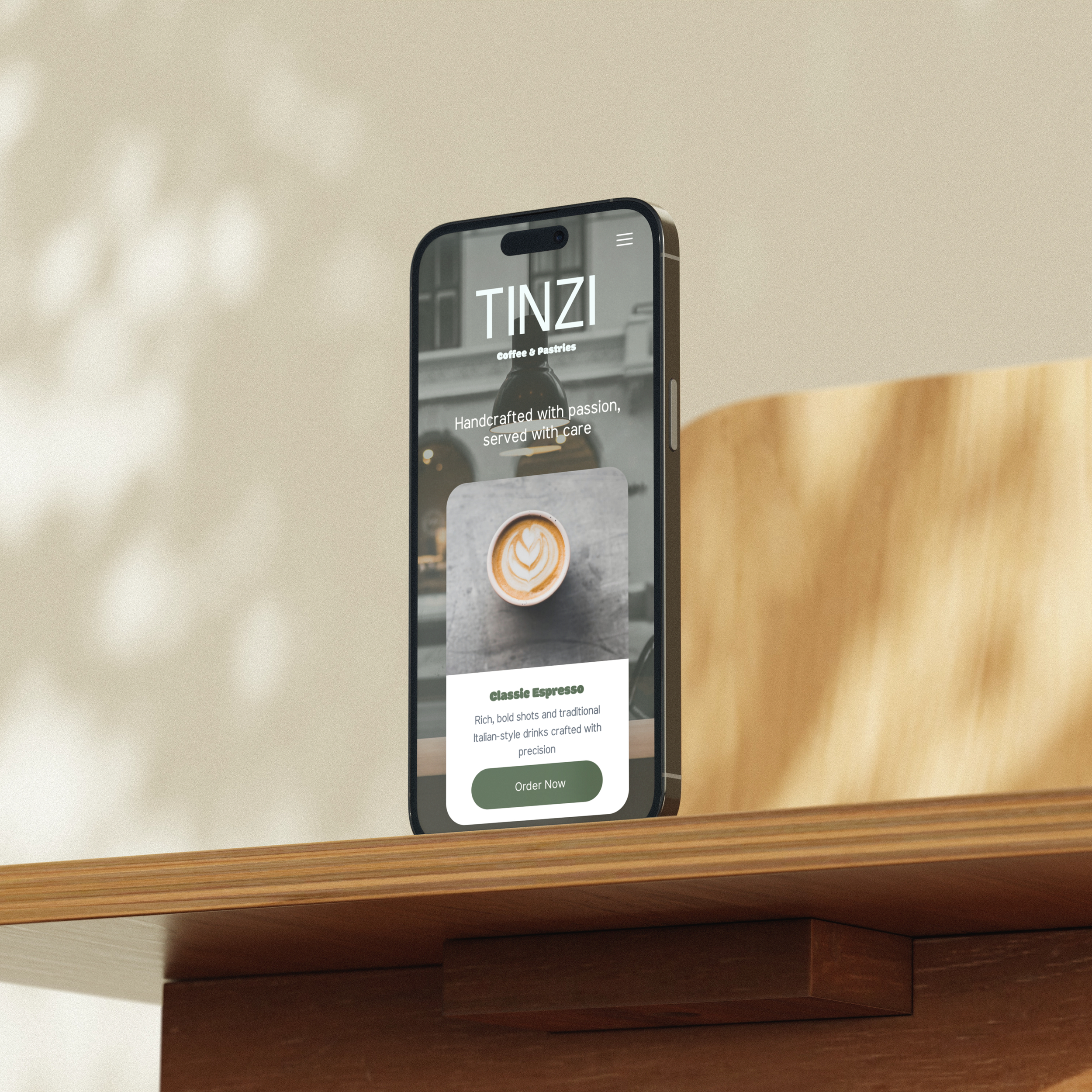 Smartphone displaying a coffee shop app named TINZI, showing a latte art image and a description for classic espresso, placed on a wooden table.