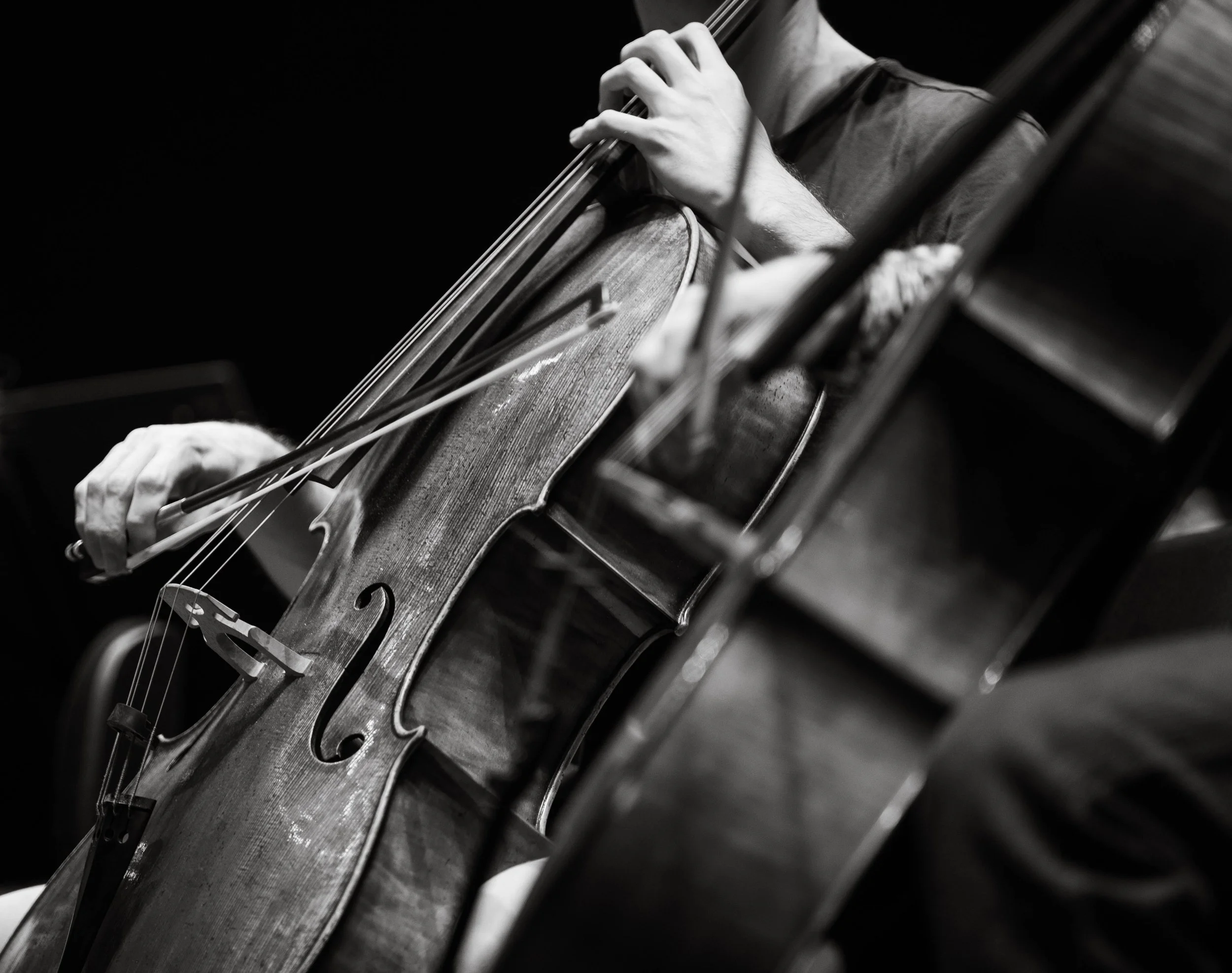 Gros plan d'une personne jouant du violoncelle en noir et blanc.