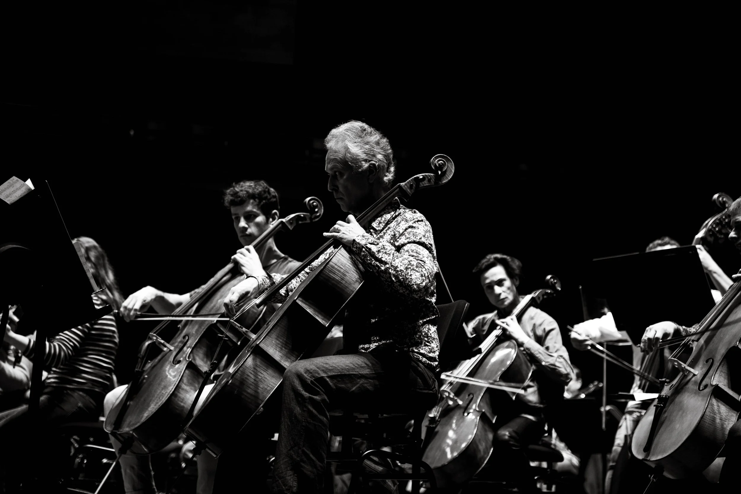 Orchestre jouant du violoncelle lors d'une performance, en noir et blanc.