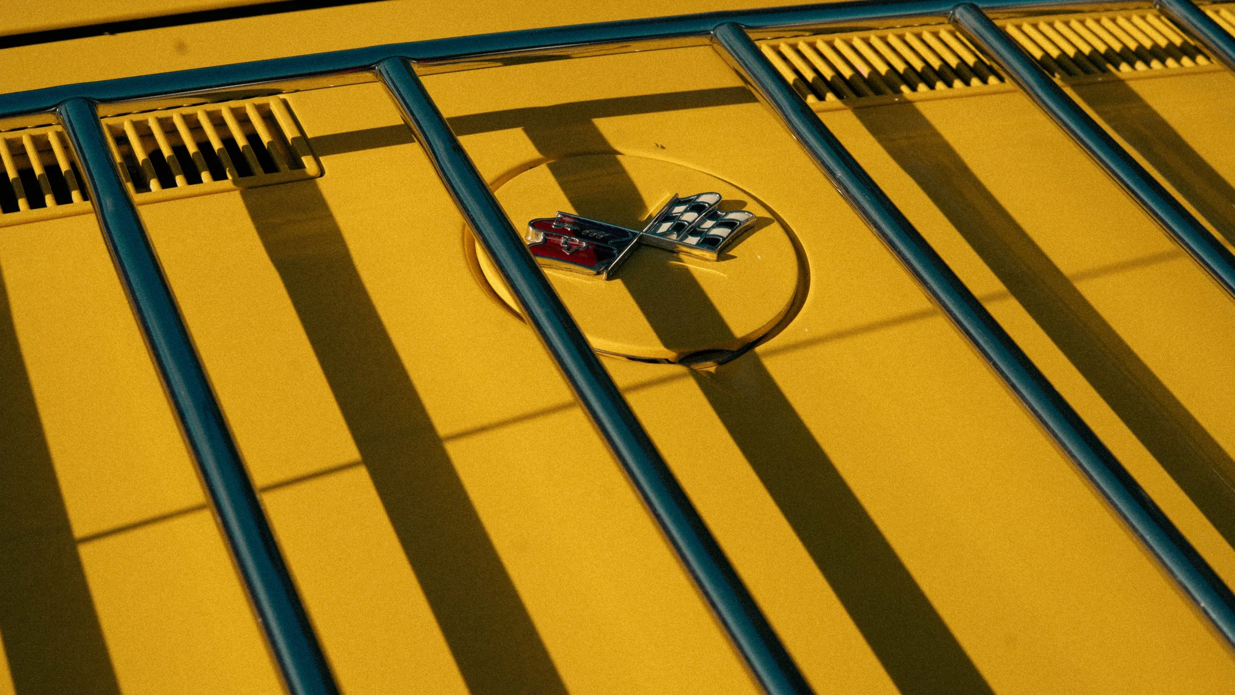 Détail du capot d'une voiture Chevrolet Corvette jaune avec un emblème en forme de drapeau et des sponsors Chevrolet et ZR1.