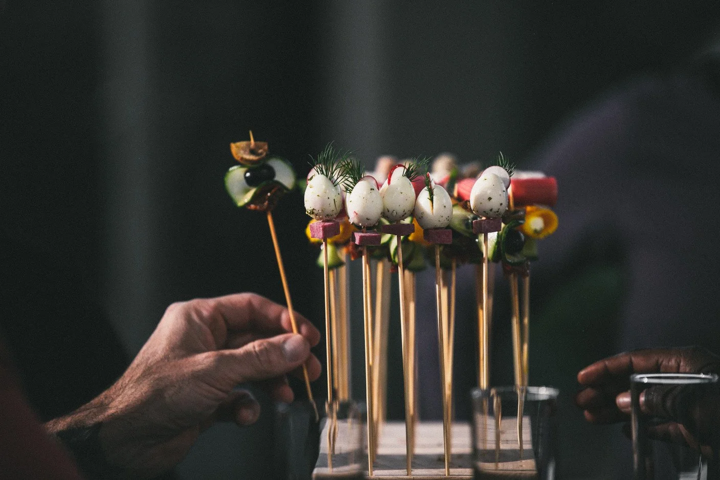 Une composition de brochettes colorées avec des œufs de caille, des légumes et des herbes, présentée sur des brochettes en bois.