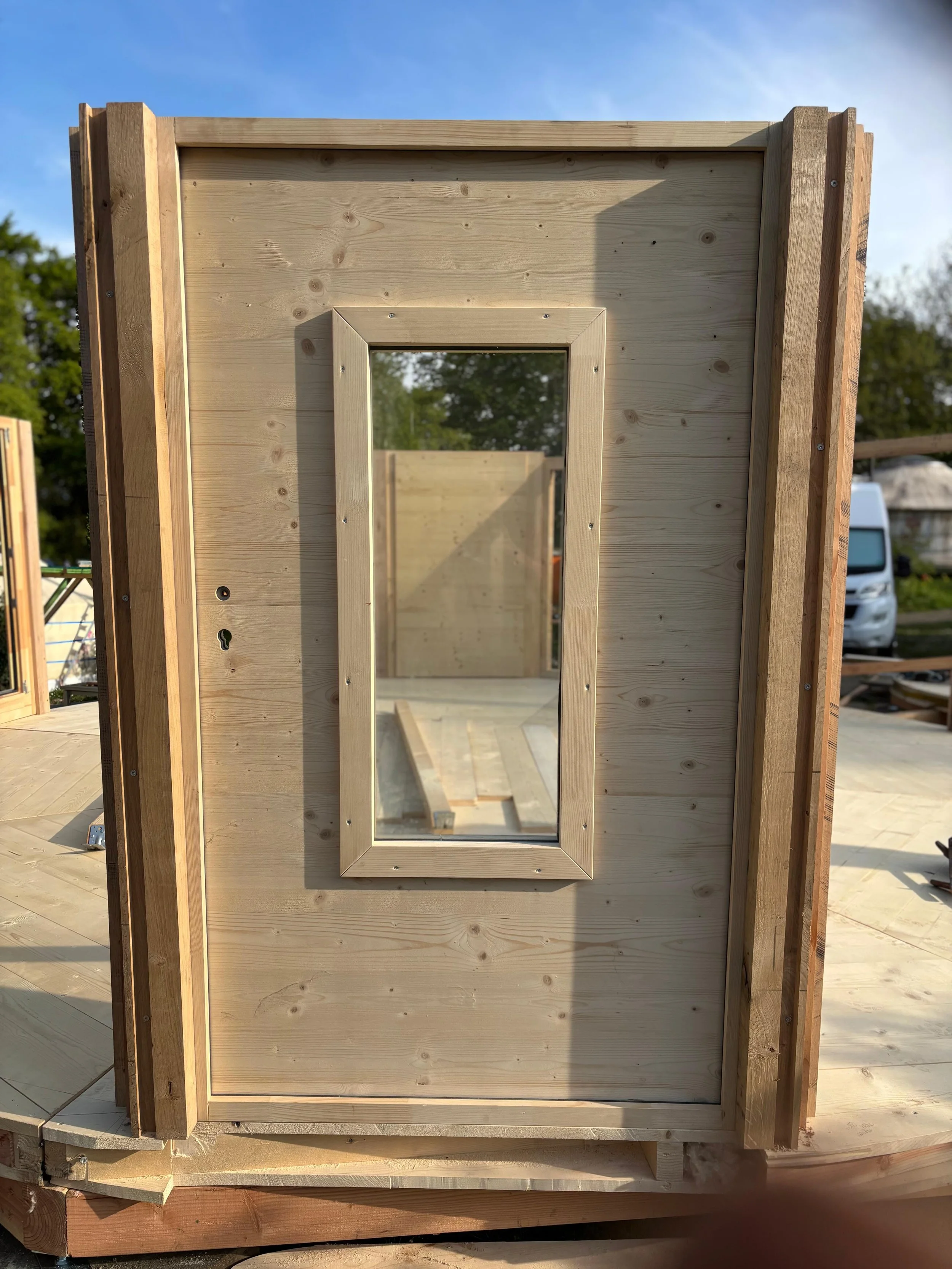 Mur en bois avec une fenêtre encadrée en construction, à l'extérieur, en milieu ensoleillé.