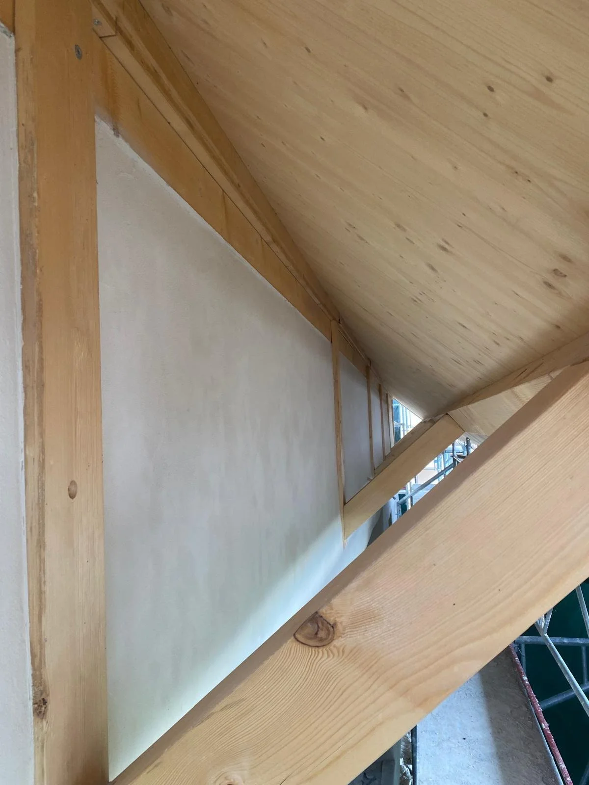 Photo montrant une poutre en bois dans une construction intérieure, avec un plafond en bois et un mur en plâtre, prise lors de travaux. Avant Toi