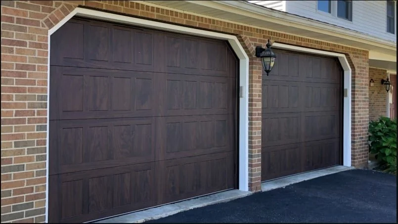 Two Dark Wooden Stamped Shaker Garage Doors on Brick House