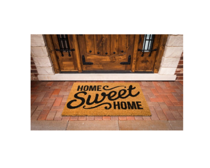 Doormat with the words 'Home Sweet Home' in black letters in front of a wooden door with brick and stone exterior.