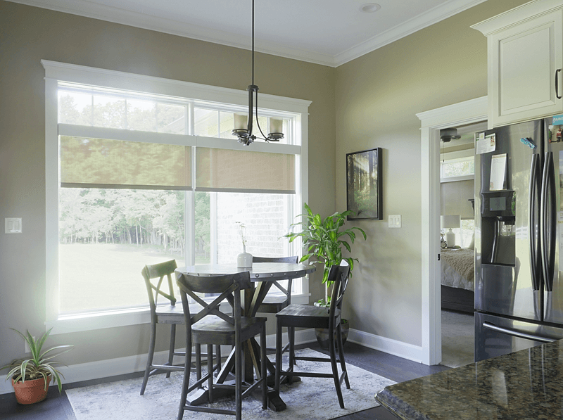 Light-filtering roller shade partially lowered on a large residential window, diffusing sunlight while maintaining a soft, natural outdoor view.