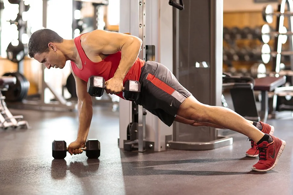 A man performing a tricep push-up with dumbbells in a gym.