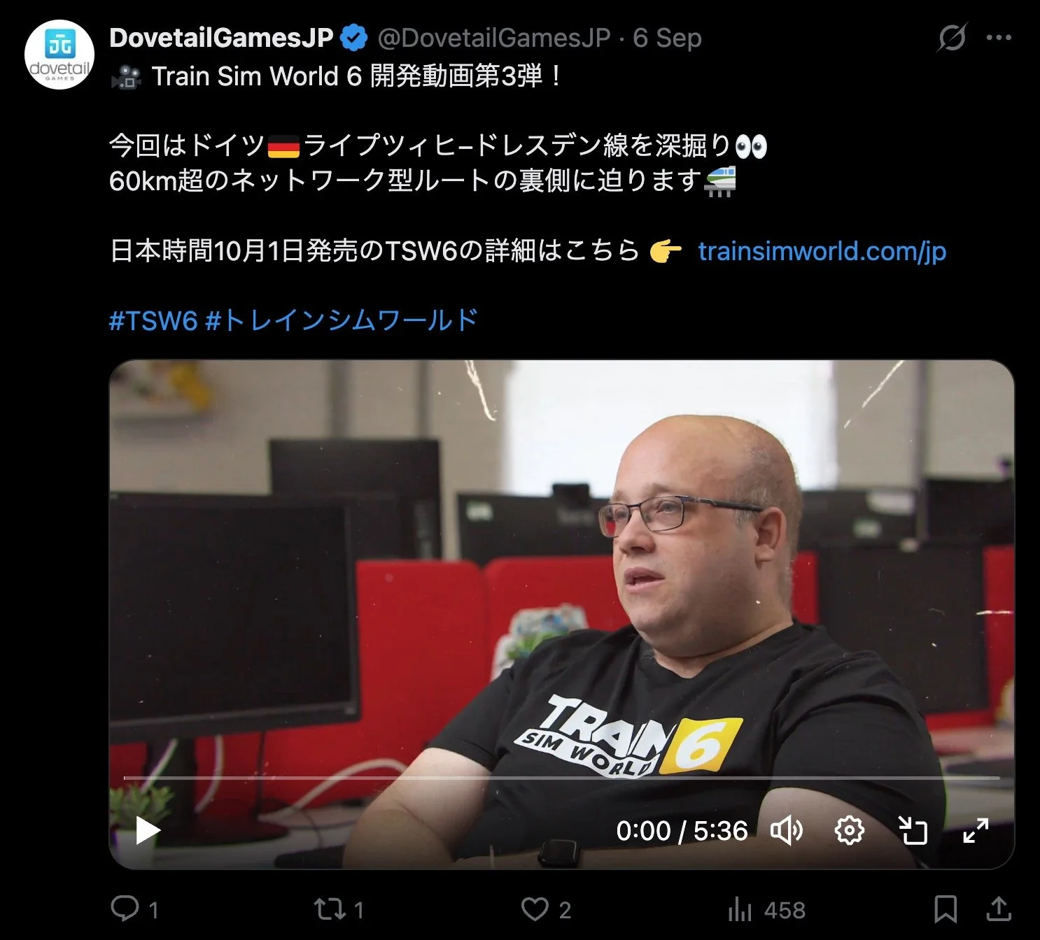 ダヴテールゲームズ_X (Twitter)_ゲーム開発者が座っている。背景にはコンピュータモニターと赤いパーティションがある。