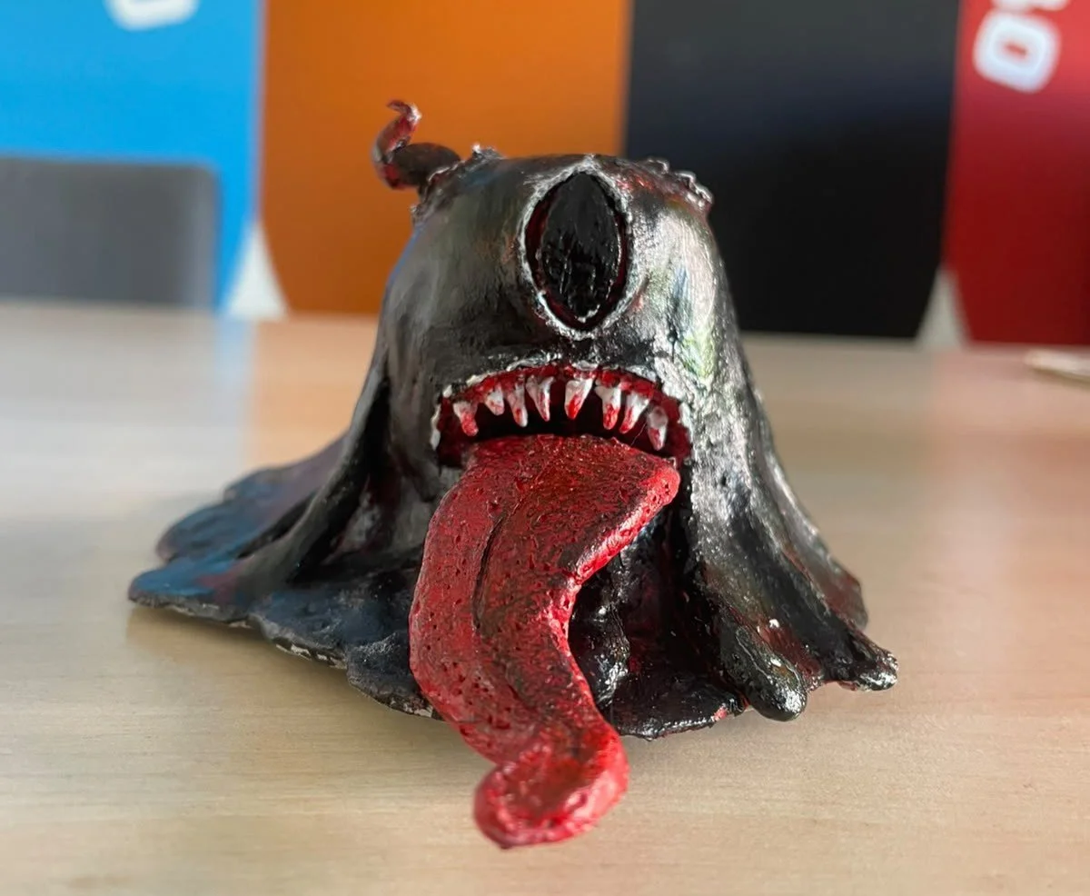 Mostriciattolo in argilla di colore nero con linguaccia e denti aguzzi, realizzato durante il laboratorio di arteterapia Manifattura Arcobaleno.