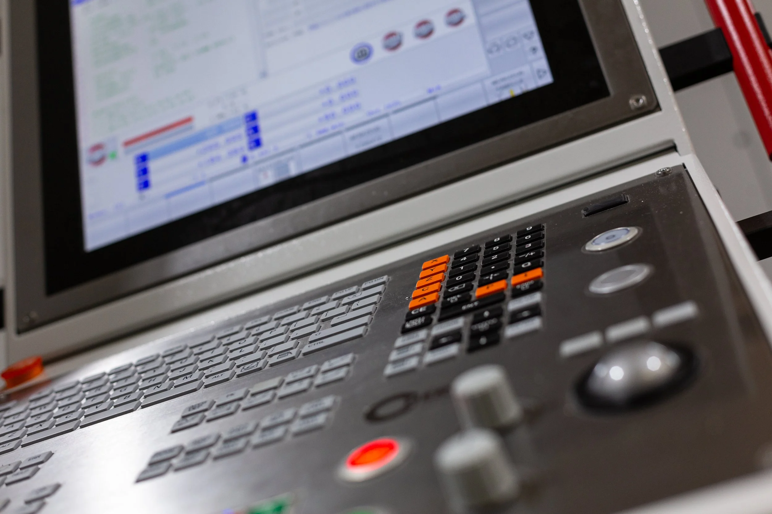 Nahaufnahme eines Kontrollpults mit Tastatur, Touchscreen und mehreren Knöpfen in einem Fahrzeug oder einer technischen Einrichtung.