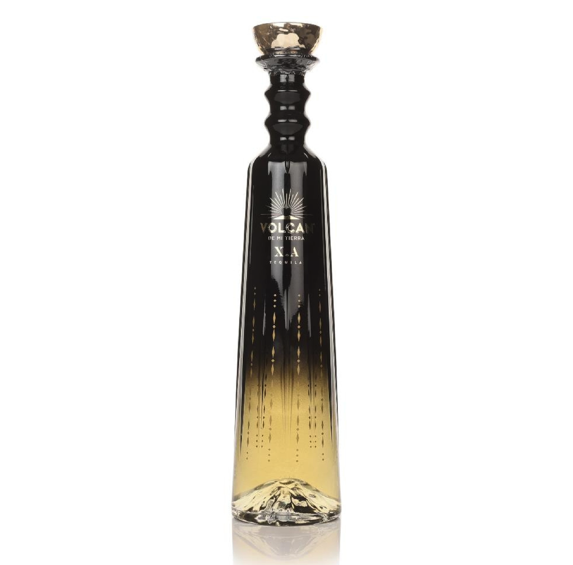 Decorative glass bottle with gradient black to gold color and label reading "Volcán de mi tierra tequila".